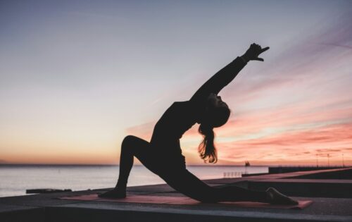 a woman doing yoga over a sunset